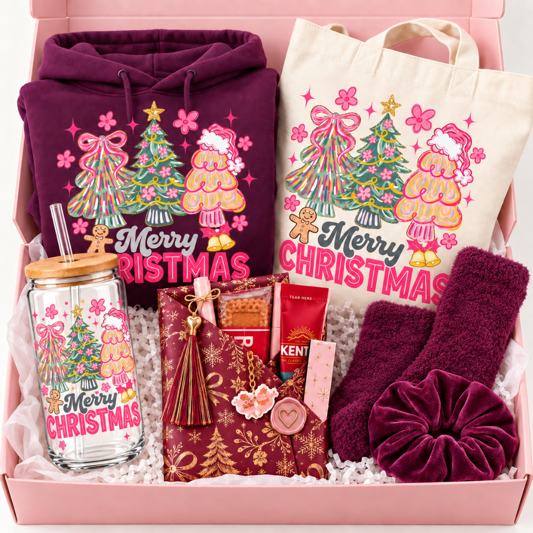 A Christmas-themed gift box set featuring a plum purple hoodie, a cream canvas tote bag, a matching glass tumbler with a wooden lid and straw, a plum purple scrunchie, a burgundy patterned pouch with a tassel, and a Kent coffee bag, all decorated with festive Christmas illustrations and arranged in a pink box.