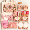 A coordinated holiday gift set arranged on a light neutral background, featuring a cream tote bag with a large Christmas village print and the words 'Sugarplum Snowfall,' 