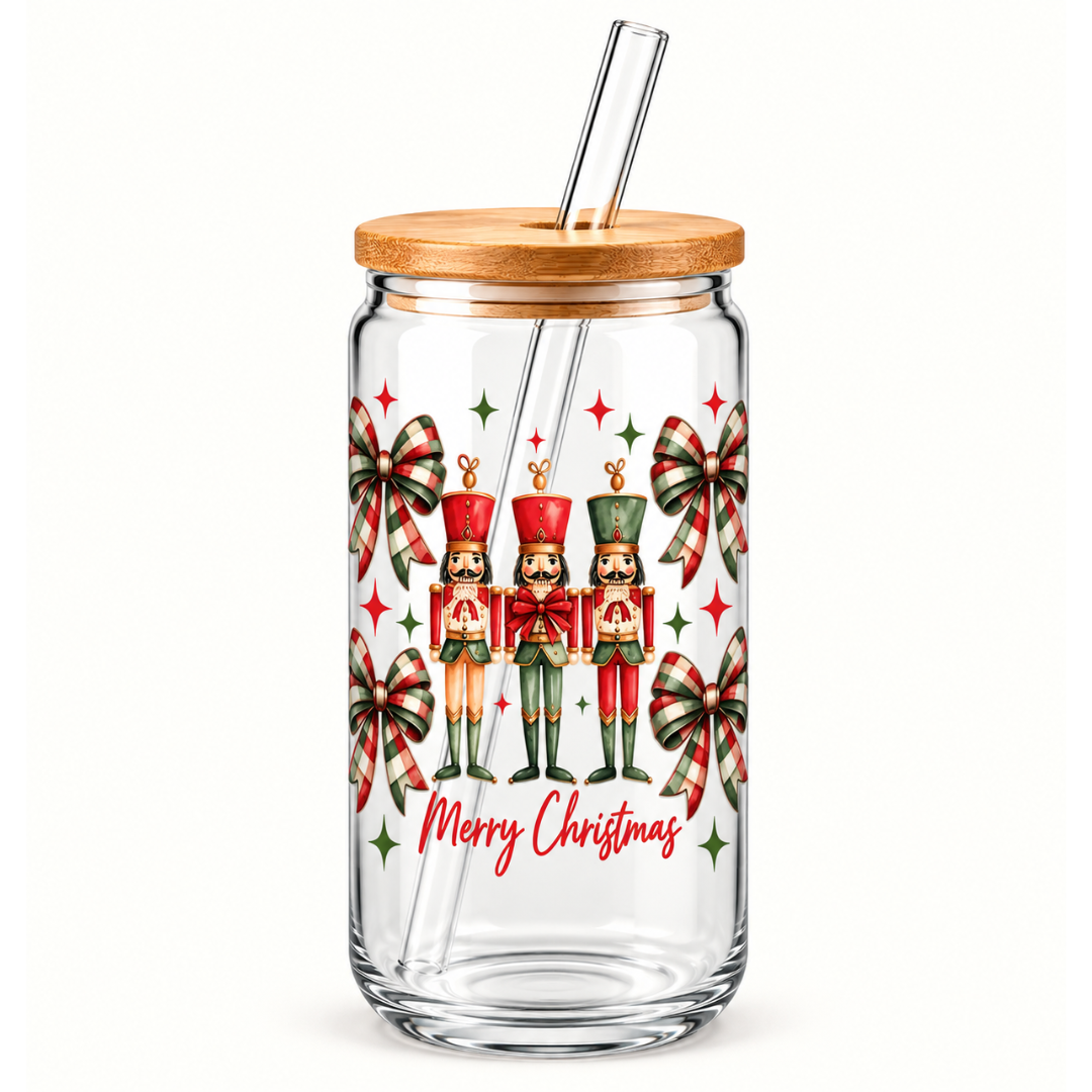 A clear glass tumbler with a bamboo lid and clear glass straw, decorated with a Christmas nutcracker and bow pattern and the text 'Merry Christmas' in red script.